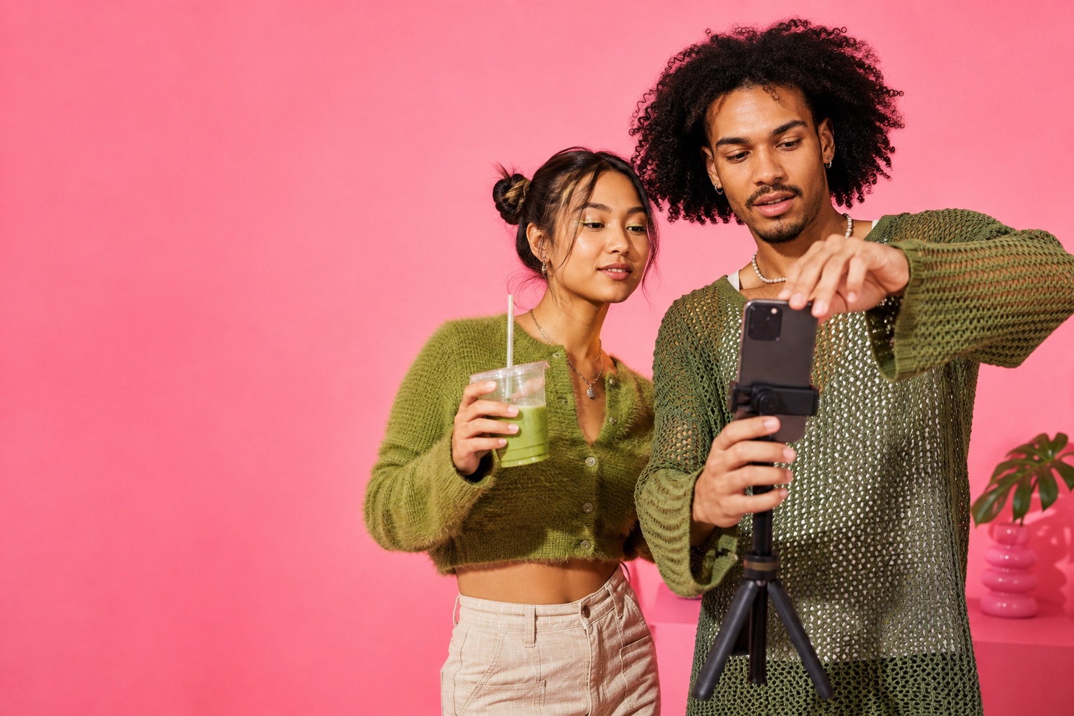 Zwei junge Creator mit Matcha und Smartphone-Stativ in einem pinken Studio